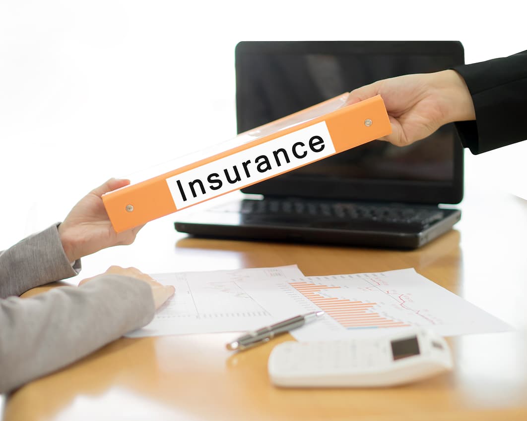 Two hands exchange an orange binder labeled 